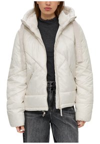 Puchowa kurtka kremowa z zamkiem z przodu, z miękkim, podszytym kapturem oraz ukośnym pikowaniem. Zawiera markowy pasek i boczne kieszenie.