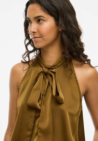 Top halter in satin verde oliva con dettaglio a fiocco sul collo. Tessuto liscio con una vestibilità drappeggiata e design minimalista.