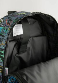 Mochila con un patrón gráfico multicolor, cierre de cremallera y forro interior negro que cuenta con secciones de etiqueta para detalles personales.