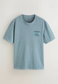 Hellblaues T-Shirt aus Baumwolle mit kurzen Ärmeln, rundem Ausschnitt und dem Schriftzug "Bozeman, Montana" auf der linken Brust.