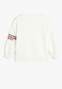Sudadera blanca hecha de tejido suave, con un cuello redondo y mangas largas. Gráfico rosa notable en la manga izquierda. Puños acanalados.