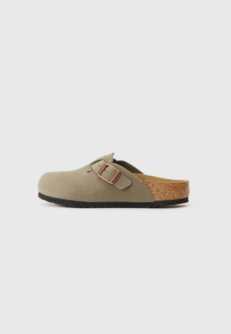 Jäljittävän vihreät puukengät, joissa on teksturoitu päällinen, säädettävä solki ja korkkipohja, varustettuna mustalla kumipohjalla pidon parantamiseksi.