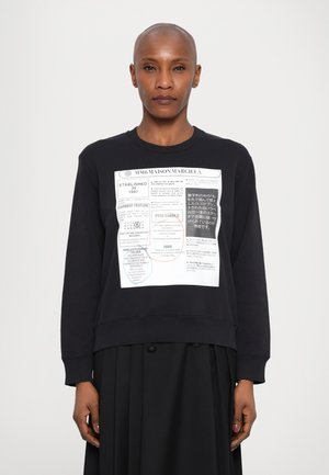 Musta collegepaita, jossa on pyöreä kaula-aukko, ja etupuolella on suuri graafinen printti, joka sisältää tekstiä ja värikkäitä ympyröitä.