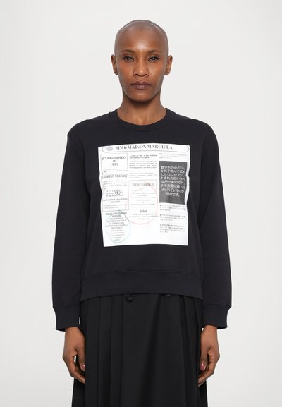 Sweatshirt noir avec encolure ras du cou, présentant un grand imprimé graphique sur le devant qui inclut du texte et des cercles colorés.