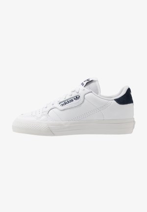 Białe niskie trampki Adidas z zapięciem na sznurówki, czarnym logo po boku i na języku oraz czarną zakładką na pięcie.