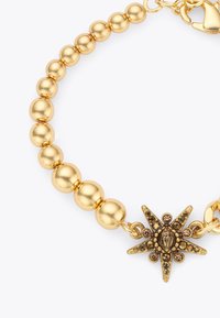 Bracciale in perline d'oro con un ciondolo a forma di stella che presenta un design di scarabeo e pietre decorative, caratterizzato da una finitura lucida e chiusura a gancio.