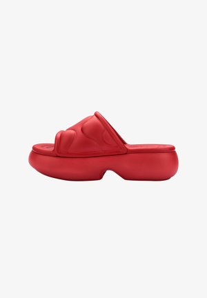 Red slide sandal featuring a thick, rounded sole and a textured upper with smooth, curved designs. Made from flexible rubber material.