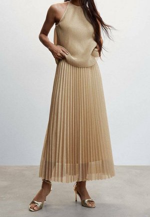 Pleated, long, beige dress made from ribbed fabric with a halter neckline. Paired with metallic, strappy high-heeled sandals.