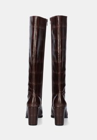 Botas marrones altas de cuero brillante con estampado de cocodrilo en relieve, con puntera cuadrada, tacón grueso y cierre de cremallera en la parte posterior.