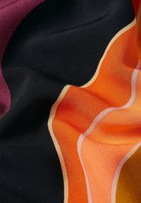 Bunt gemustertes Gewebe mit glatter Textur, das wellenförmige Muster in Orange, Lila und Gelb auf einem schwarzen Hintergrund zeigt.