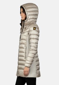 Beige donzen jas met capuchon, voorzien van een doorgestikt reliëf, verticale stiksels en een logopatch op de linker schouder.