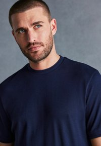 Navyblauwe t-shirt met korte mouwen en een ronde halslijn, gemaakt van zachte stof, met een subtiele rek en minimale stikseldetails.