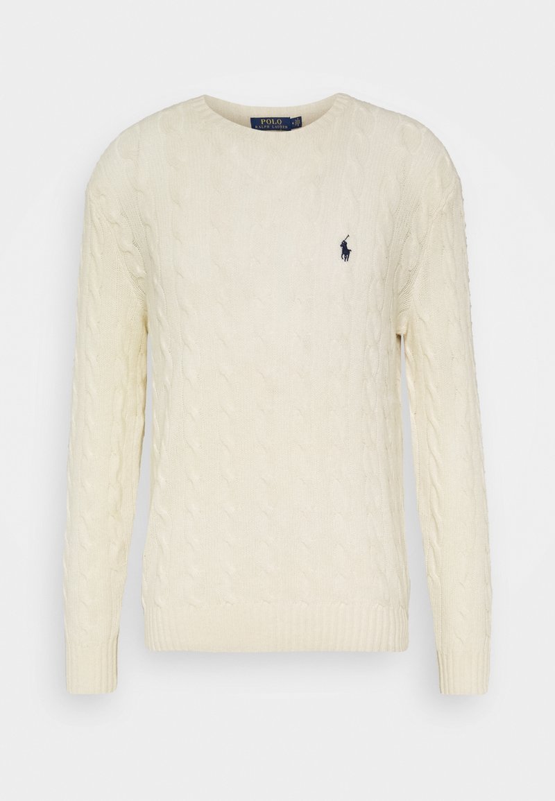 Krämfärgad bomullssweater med kabelstickning, lång ärm, rund halsringning, ribbade muddar och en liten marinblå logotyp på vänster bröst.