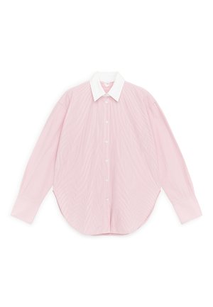 Chemise rose clair à manches longues avec boutons, larges poignets et col pointu blanc contrastant, étalée à plat sur fond blanc.