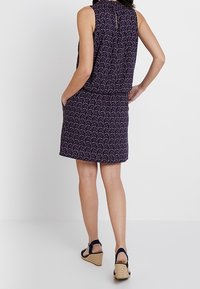 Ärmelloses Kleid in Marineblau mit einem floralen Muster in Pink und Weiß. Verfügt über eine taillierte Taille, Seitentaschen und einen leicht ausgestellten Rock.