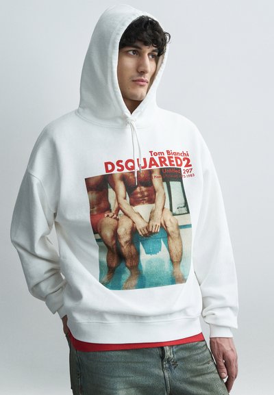 Sweat à capuche blanc avec un imprimé graphique représentant deux figures assises. Le tissu est doux avec une finition légèrement texturée. Accents de texte rouge et noir.