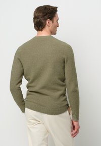 Maglione verde oliva realizzato in materiale a maglia testurizzata, con scollatura rotonda e maniche lunghe, orlo aderente e dettagli di cucitura visibili.