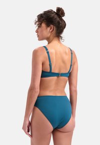 Tyrkysový bikini s nastavitelnými ramínky a zapínáním na klip, se zvýšeným střihem spodního dílu, vyrobený z hladkého, elastického materiálu.