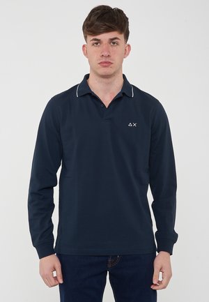 Polo a maniche lunghe blu navy con colletto, rifinitura bianca e un piccolo logo sul lato sinistro del petto. Realizzato in un tessuto liscio e traspirante.