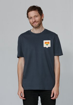 Marineblauw katoenen T-shirt met een hart en een regenbooggradiëntgrafiek op een lichte achtergrond, korte mouwen en een standaard ronde hals.