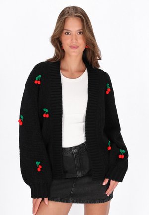 Schwarze Strickjacke mit geripptem Design, übergroßen Ärmeln und roten Kirschstickereien auf der Vorderseite und den Ärmeln.