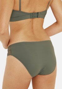 Ensemble de bikini vert olive avec un détail en maille sur les côtés et une fermeture à crochet à l'arrière du haut, avec une finition lisse dans l'ensemble.