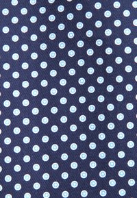 Tessuto blu navy con un motivo ripetuto di cerchi bianchi piccoli e equidistanti, ognuno contenente un punto blu chiaro al centro.