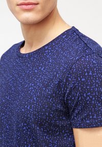 Camiseta azul marino hecha de tela suave, con un patrón geométrico en diferentes tonos de azul, con cuello redondo y mangas cortas.