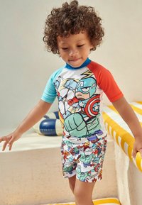 Børns svømmesæt med en flerfarvet kortærmet top med superheltemønstre og matchende shorts i lignende design med livlige farver.