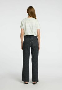 Ljusrandig t-shirt med kort ärm, kombinerad med hög midja och vida svarta jeans i denim. Sött material med en avslappnad passform.