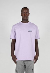 Tricou din bumbac de culoare mov deschis, cu guler rotund, mâneci scurte și un logo mic negru pe pieptul stâng. Textură netedă, croi lejer.