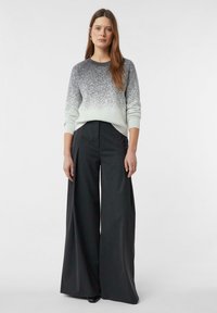 Jasnoszary sweter z efektem ombre, przechodzącym w ciemniejszy szary przy krawędzi. Połączony z czarnymi, szerokimi spodniami z wysokim stanem.