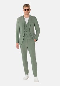 Hellgrüner Dreiteiler mit einfarbigem Textur, taillierter Passform, abgesetzten Revers, fünf Knöpfen und weißen Sneakers.