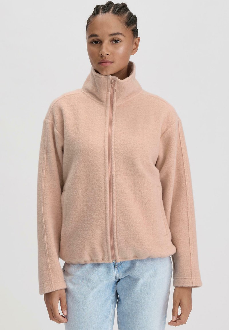 Fleecejacke in zartem Pastellrosa, mit hohem Kragen, Vorderreißverschluss und lockerer Passform. Der Stoff hat eine glatte Textur mit dezenten Nähdetails.