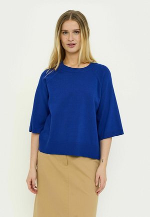 Blauwe gebreide trui met een ronde hals, afhangende schouders en korte mouwen. Heeft een geribde zoom en subtiele steekdetails langs de schouders.