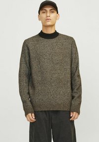 Pull en tricot marron à motifs, avec un col côtelé noir haut et des manches longues, offrant une coupe décontractée et des poignets côtelés.