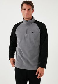 Fleece-pullover i grå med sorte raglanærmer, halv-lynlås ved halsen og lille logo på brystet. Blød tekstur med en afslappet pasform.