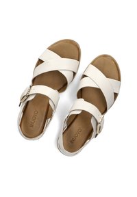 Sandali bianchi con cinturini incrociati, una fascia regolabile con fibbia e una soletta imbottita marrone. Texture in pelle liscia e suola piatta.