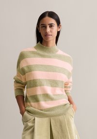 Gestreifter Pullover in sanftem Pink und olivgrün, mit einem hohen gerippten Kragen und einer lockeren Passform. Texturiertes Material mit einem gemütlichen Aussehen.