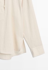 Lichtbeige lange mouwen shirt gemaakt van zachte stof, met een knoopsluiting, zijslitsen en een afgeronde zoom.