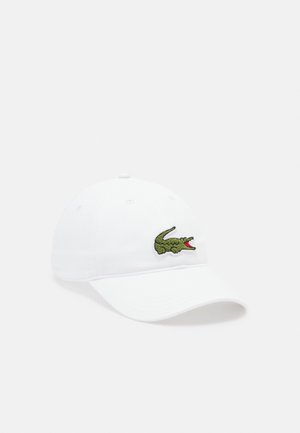 Biała bawełniana czapka baseballowa z wygiętym daszkiem i haftowanym zielonym logo krokodyla z przodu. Posiada sześć otworów wentylacyjnych.