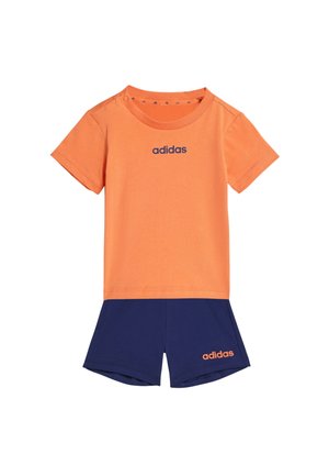 Camiseta naranja de manga corta Adidas combinada con pantalones cortos azul marino, ambos con el logotipo de Adidas en colores contrastantes.
