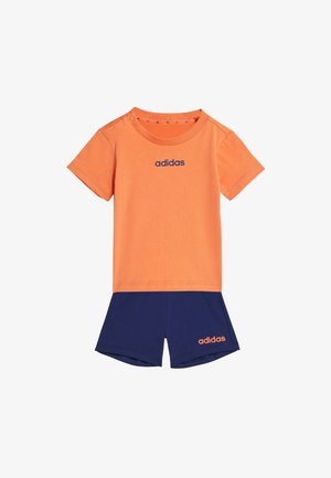 Camiseta naranja de manga corta Adidas combinada con pantalones cortos azul marino, ambos con el logotipo de Adidas en colores contrastantes.