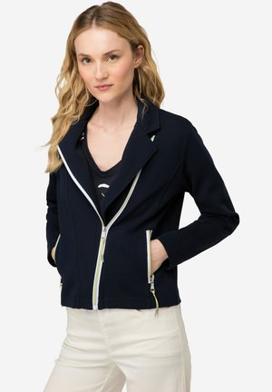 Veste marine avec un col cranté, devant zippé blanc et accents vert lime, dotée de deux poches latérales zippées et d'une coupe ajustée.