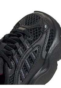 Black athletic shoe featuring a mesh upper, rubber accents, and textured sole. Notable details include multiple air holes and sleek lines.
