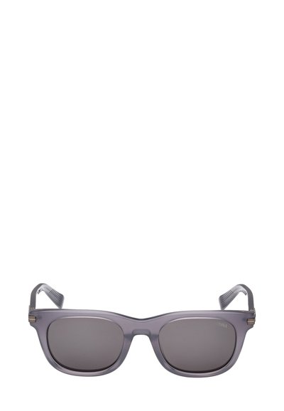 Harmaat, suorakulmaiset aurinkolasit, joissa tummat linssit. Puoli läpikuultava kehys, teksturoidut sankarit ja minimaliset metallikoristeet saranoiden lähellä.