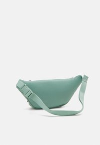 Síťovaná taška přes rameno v světle tyrkysové barvě s zakřiveným tvarem. Obsahuje široký popruh a nastavitelnou sponu pro bezpečné nošení. Texturovaná surface pro lepší uchopení.