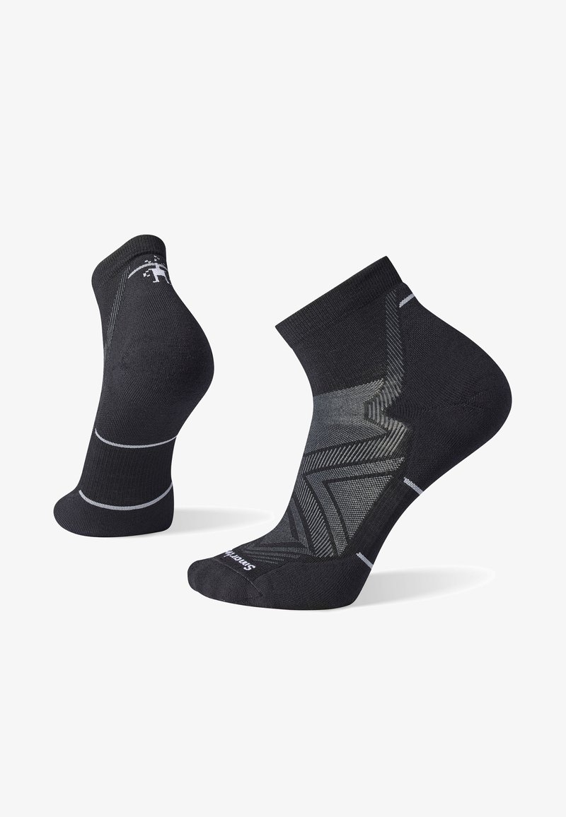 Sorte atletiske sokker med teksturerte mønstre, polstret konstruksjon og hvite detaljer. Rund tå og midtleggsdesign for komfort og støtte.