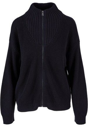 Maglione lavorato a maglia con zip di colore blu scuro, caratterizzato da un alto colletto, texture a costine e spalle abbassate. La zip si estende lungo la parte anteriore.