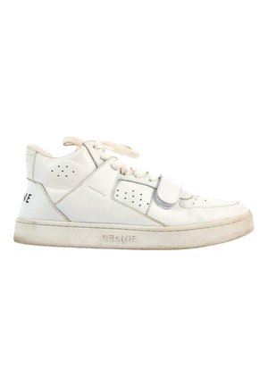 Biały, skórzany sneaker niskiego profilu z sznurowadłami, paskiem na rzep, perforowanymi detalami i lekko zużytą podeszwą.